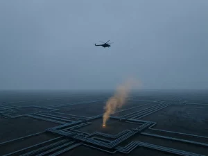 Helicopter silhouette hovering over geometric pipeline grid with amber-marked leak detection point and faint translucent plume rising below.